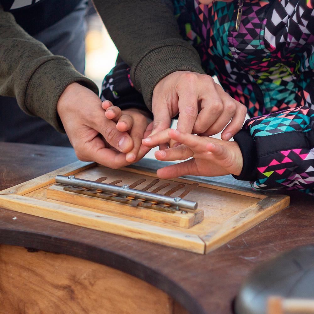 Крупным планом: заботливые руки. Арт-медиатор помогает юной посетительнице выставки нащупать звучащие лепестки калимбы